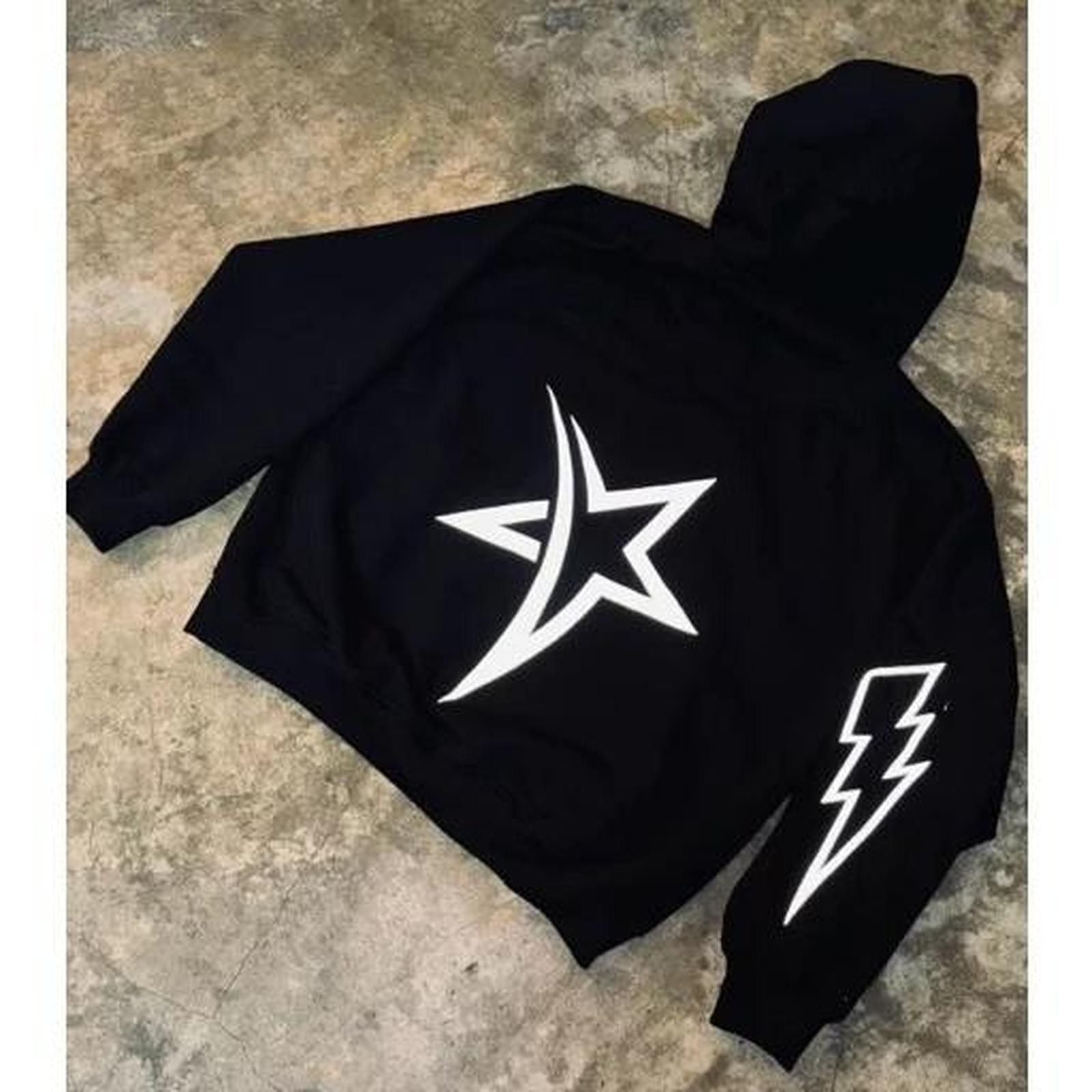 Black hoodie with white star and lightning bolt design on a textured surface