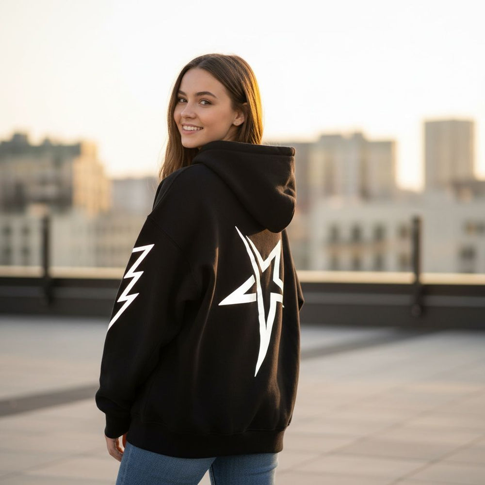 Woman wearing a black hoodie with white designs on a rooftop with cityscape background